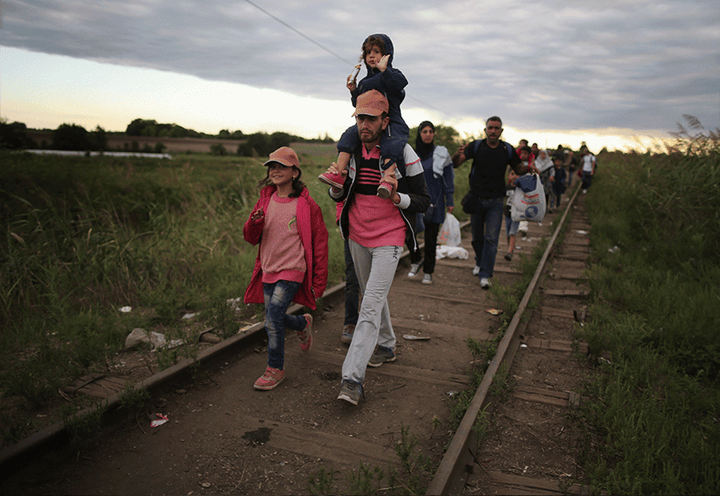Migrants and refugees cross the border from Serbia into Hungary along the railway tracks close to the village of Roszke on Se