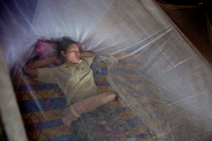 TAK, THAILAND - JUNE 6: A mother rests under a mosquito net as her newborn baby rests in a n incubator near by at the SMRU hospital maternity ward inside the Mae La refugee camp June 6, 2012 in Tak province, Thailand.