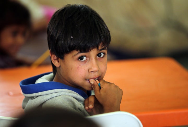 A Syrian refugee boy attends class at an unofficial refugee camp in the area of Arida, north of Beirut, on June 15, 2015. Rig