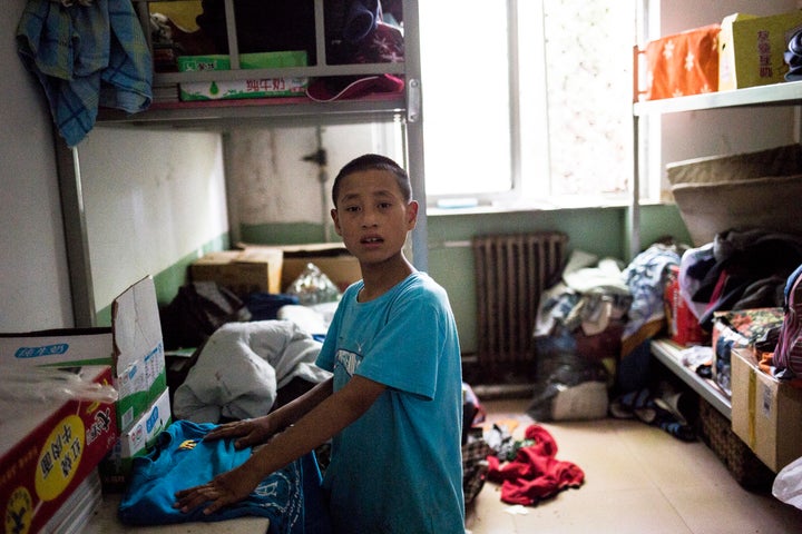 Jingtao, 14, tries to find clothes for his trip to Beijing in the storage room.