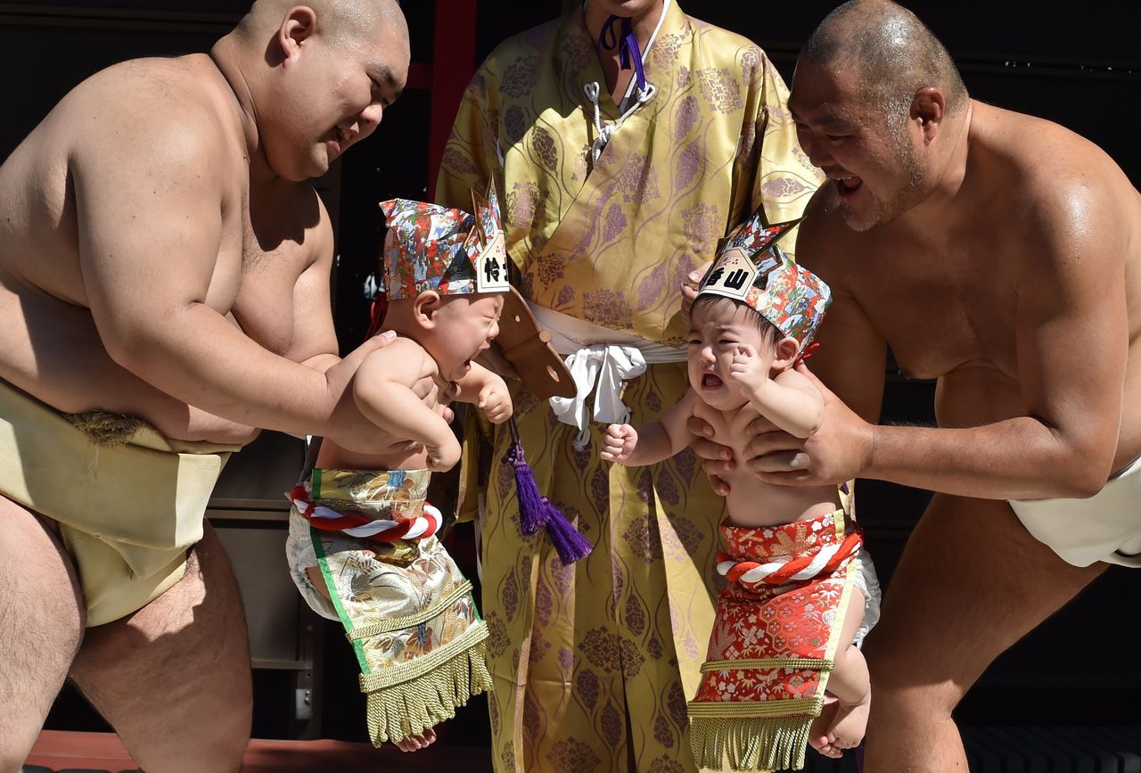 Sumo wrestlers hold up crying babies during a 'Baby-cry Sumo' event at the Irugi Shrine in Tokyo on Sept. 20, 2015. Japanese parents believe that sumo wrestlers can help make babies cry out a wish to grow up with good health.