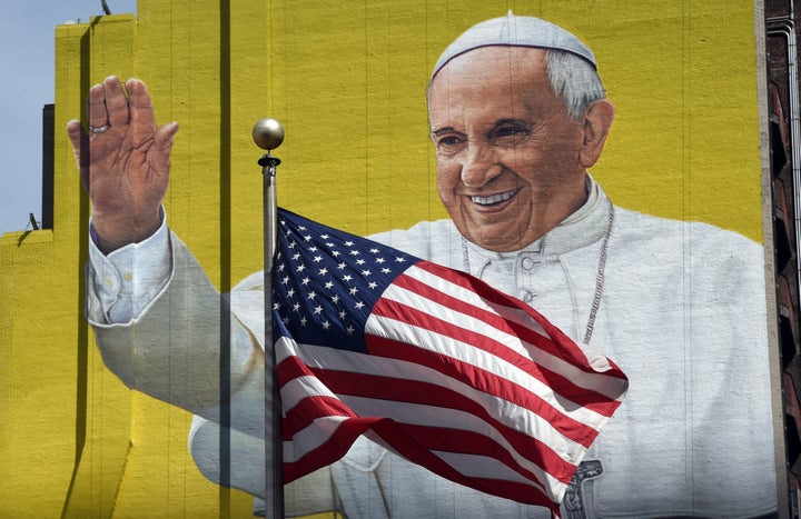 A US flag blows in the wind in front of a mural of Pope Francis across the street from Madison Square Garden in New York September 21, 2015 as the city prepares for his visit.