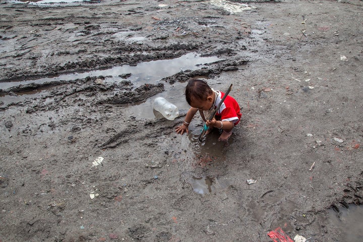 KATHMANDU, NEPAL - AUGUST 13: A young boy plays in the mud in a flooded lane inside the Chuchepati displacement camp on August 13, 2015 in Kathmandu, Nepal. About 7,144 people, hailing from different affected districts by the earthquake that hit Nepal, currently live in Chuchepati camp, with access to only 35 toilets and the help of only a few NGOs. Approximately 60,000 people are still living in over 100 official displacement camps throughout the affected districts. Living conditions in the camps are dire, with limited or non-existent access to sanitation services, clean water and food, and health services. These conditions have been made worse by heavy monsoon rains, as the camps most often lack drainage systems and are prone to flooding. (Photo by Omar Havana/Getty Images)