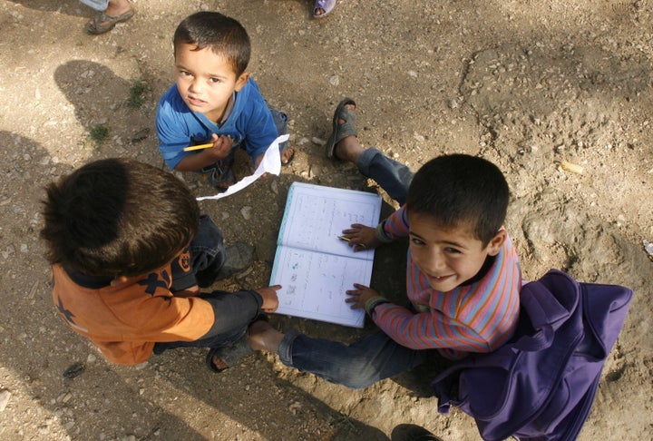 Boys play with a school book at a UNHCR's camp for Syrian refugees in south Lebanon.