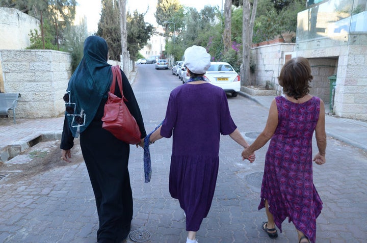 Three women, including Elana Rozenman, Abrahamic Reunion co-founder and founder of TRUST-Emun, center, hold hands during the interfaith peace walk between the eastern and western parts of Jerusalem on Sept. 21, 2015, after an interfaith group gathering between Jews and Muslims.