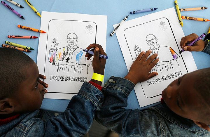 Kaydn Dorsey, 4, left, and Lionel Perkins, 4, draw on a coloring sheet bearing the image of Pope Francis as they wait for him to arrive on a visit to Catholic Charities of the Archdiocese of Washington on Sept. 24, 2015, in Washington.