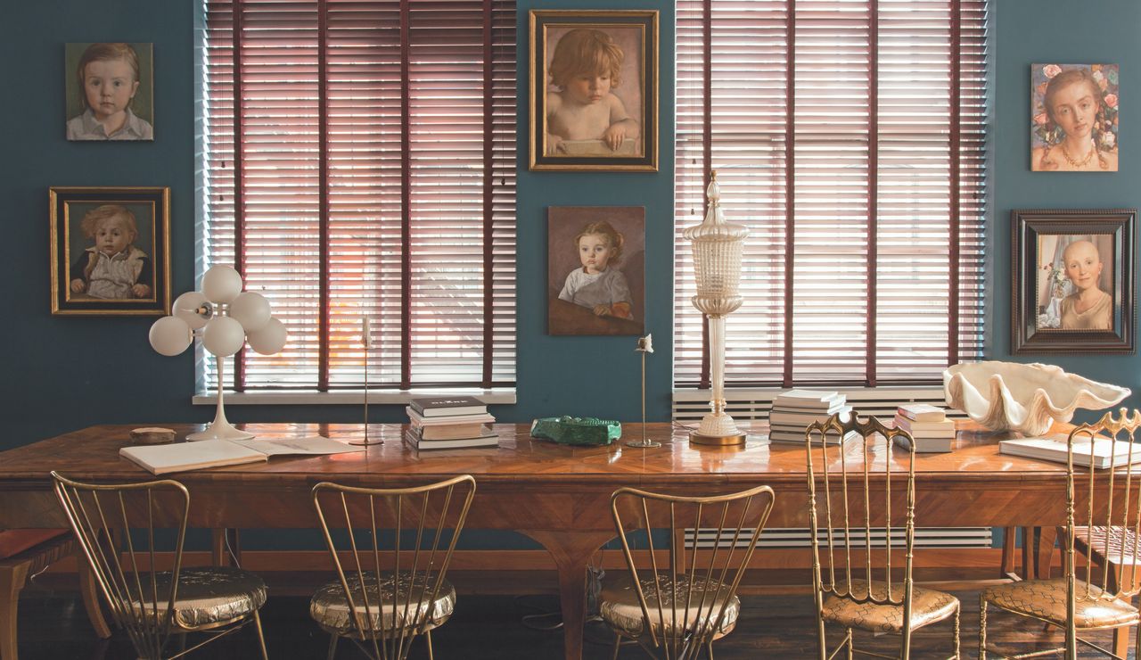 Home of John Currin and Rachel Feinstein: Family portraits by Currin of Feinstein and their three children overlook the dining room table. On the bottom right, Currin's painting of a bald woman immortalizes their beloved dog Chewy, depicted in the background. The 2001 paintings is called "Portrait of Chewy."