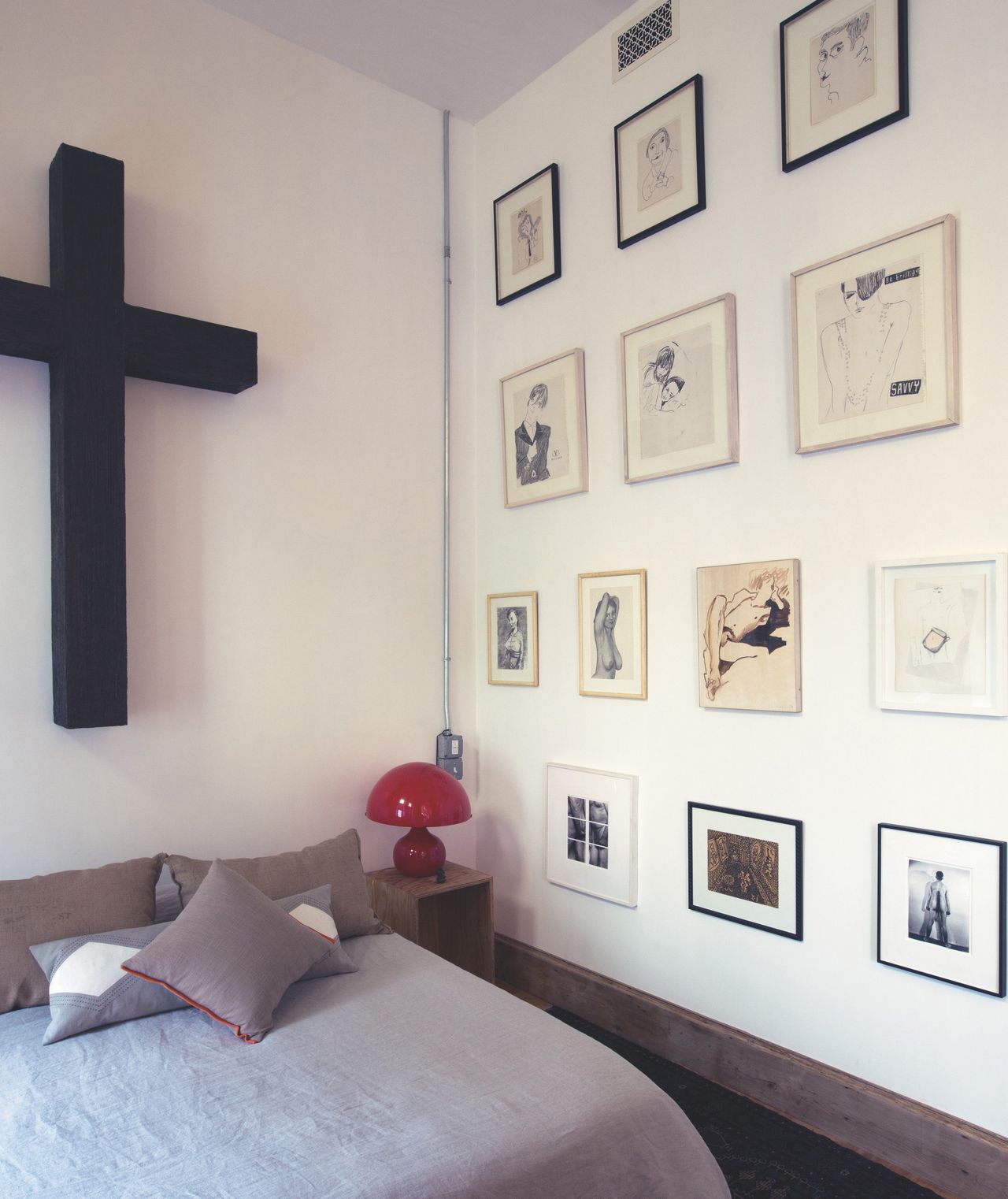The home of Ugo Rondinone: A 2006 Valentin Carron cross, which Rondinone calls "a bit of a mock," hangs above his bed, while a montage of nudes, including work by John Currin, Karen Kilimnik and Andy Warhol, fills the adjacent wall. "You see the masculine and the feminine here," explains Rondinone about his considered arrangement.