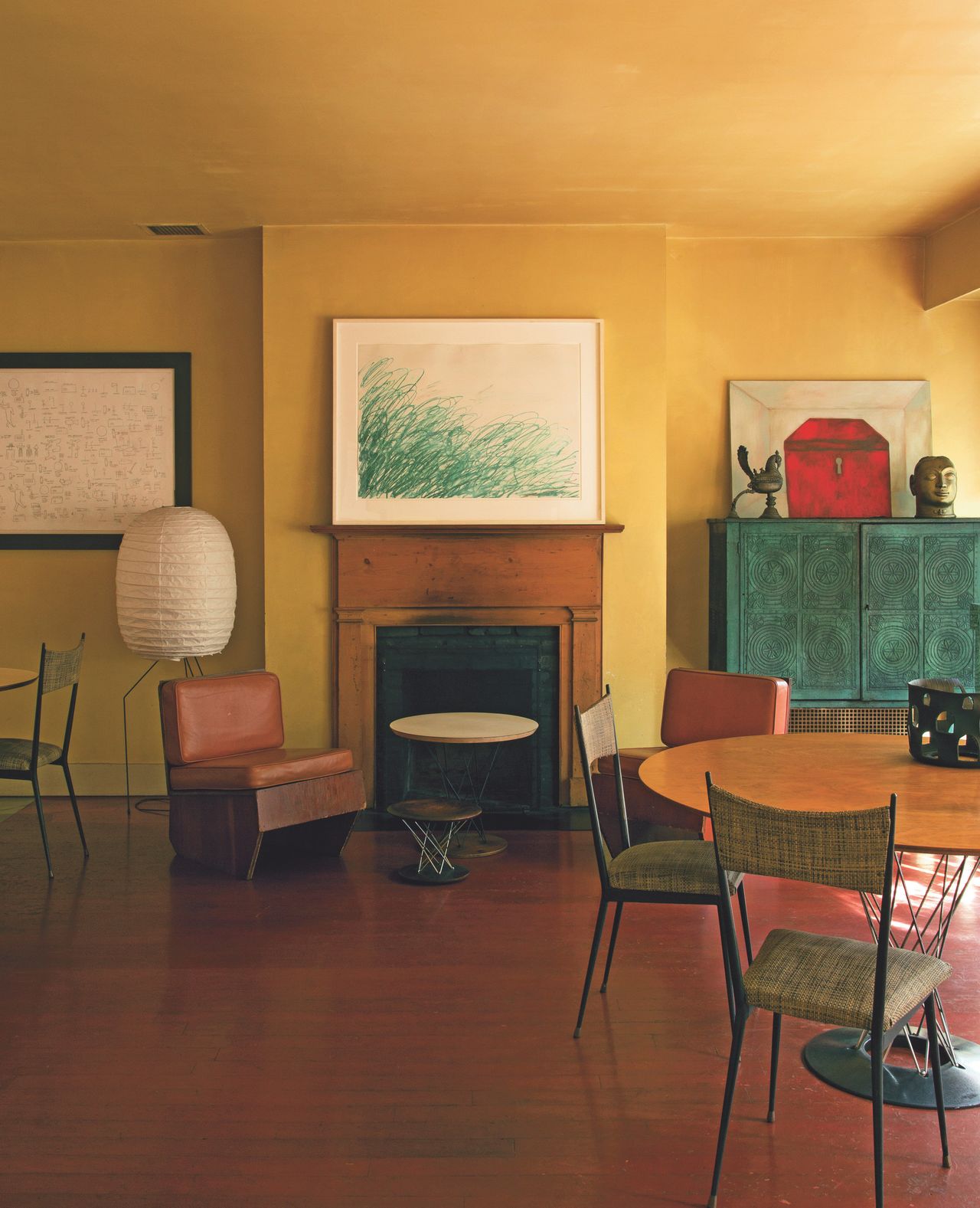 The home of Francesco Clemente: A drawing by Cy Twombly over the fireplace is flanked by a Jean-Michel Basquiat drawing and a painting by Clemente in the dining area. The furniture includes tables by Isamu Noguchi and wooden chairs by Frank Lloyd Wright.