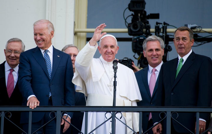 Pope Francis, joined by politicians, waves from the Capitol building following his speech to a joint meeting of Congress on Sept. 24, 2015.