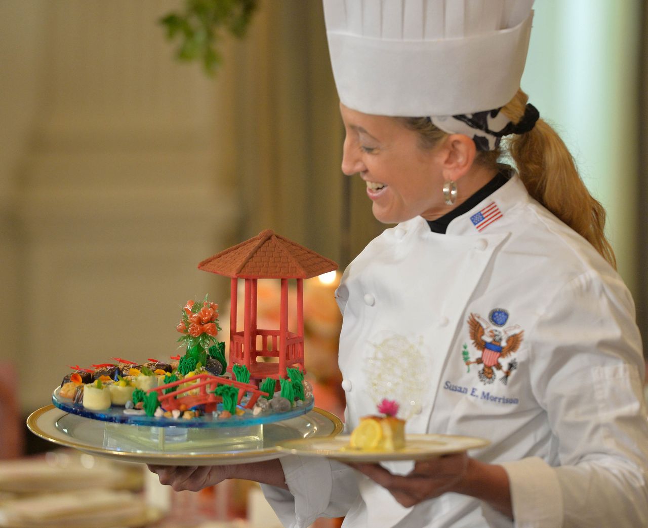 The pastry chef displays a dessert featuring a Chinese-style chocolate pavilion and bridge.