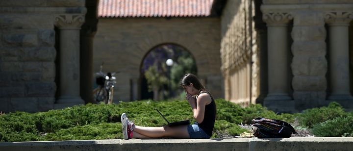 A woman studies on the campus of Stanford University. 
