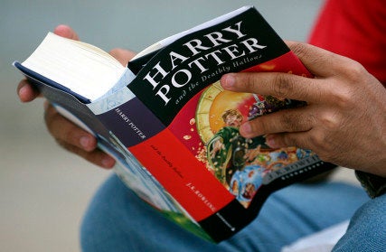 A fan reads “Harry Potter and the Deathly Hallows” by J.K. Rowling as he sits outside a bookstore in the western
