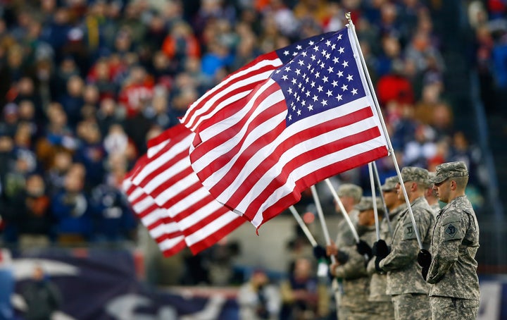 Military members hold flags before a playoff game between the New England Patriots and the Baltimore Ravens at Gillette Stadium on Jan. 10, 2015 in Foxboro, Massachusetts.