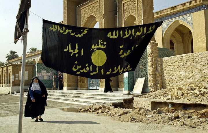 An Iraqi woman walks past a jihadi banner in Baghdad in 2004.