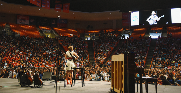 Caroline Jones performs on stage with her guitars, banjo and piano.