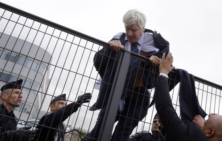 Director of Air France in Orly Pierre Plissonnier, nearly shirtless, tries to cross a fence, helped by security and police officers, after several hundred employees invaded the Air France offices.