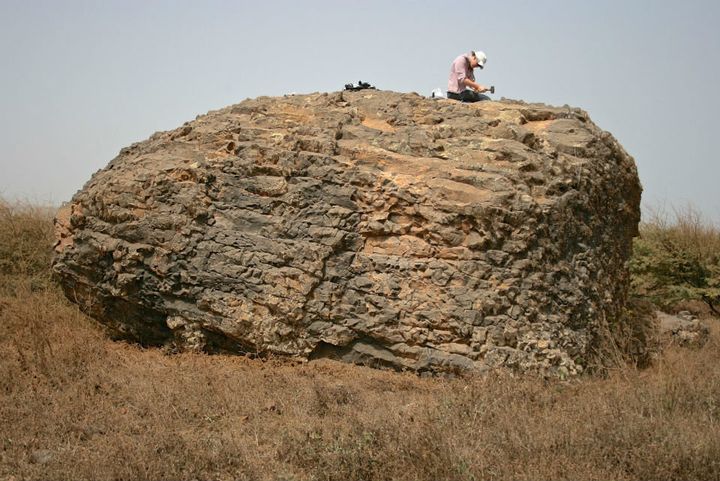 The wave generated by Fogo's collapse may have swept boulders like this one up from the shoreline into Santiago Island's highlands. Here, a researcher chisels out a sample of rock to establish the date of the tsunami wave.