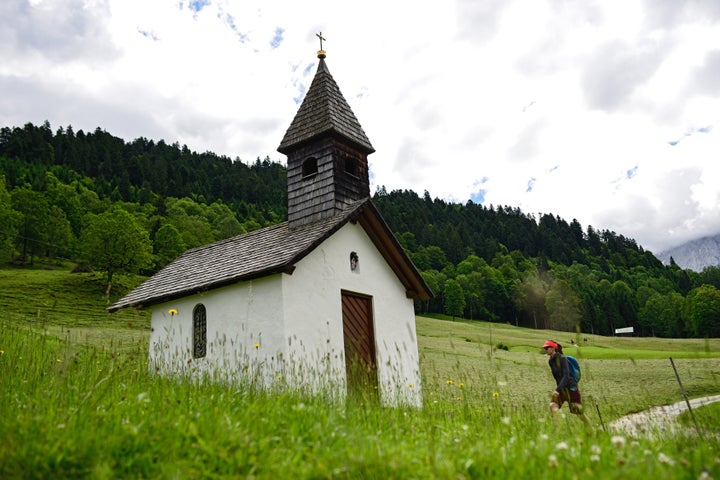 A hiker walks towards a small chapel in the Bavarian Alps on June 24, 2015, near Garmisch-Partenkirchen, Germany.