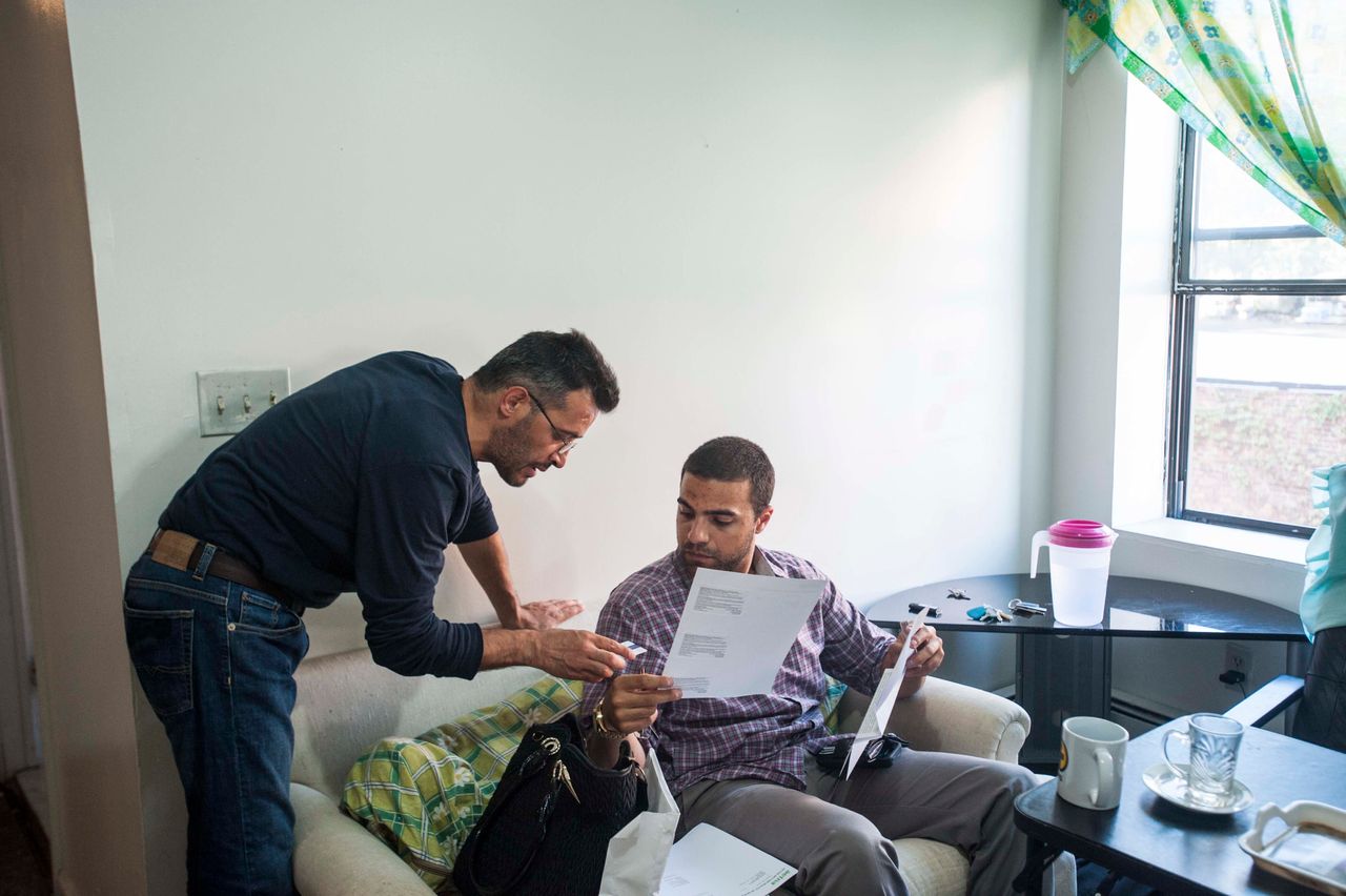 Mohamed, left, goes over paperwork with Mahmoud Mahmoud, director of the Church World Service's Jersey City branch. CWS is one of nine national refugee resettlement agencies that work with the State Department and the U.N. refugee agency.