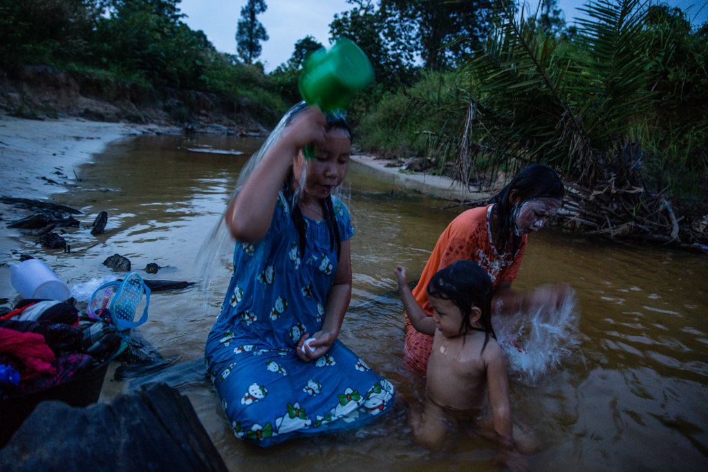 Locals bathe in the river next to the area where 35 homes were destroyed by police and personnel from Asiatic Persada in 2011. Some villagers say that the water has been polluted by runoff from the plantation.