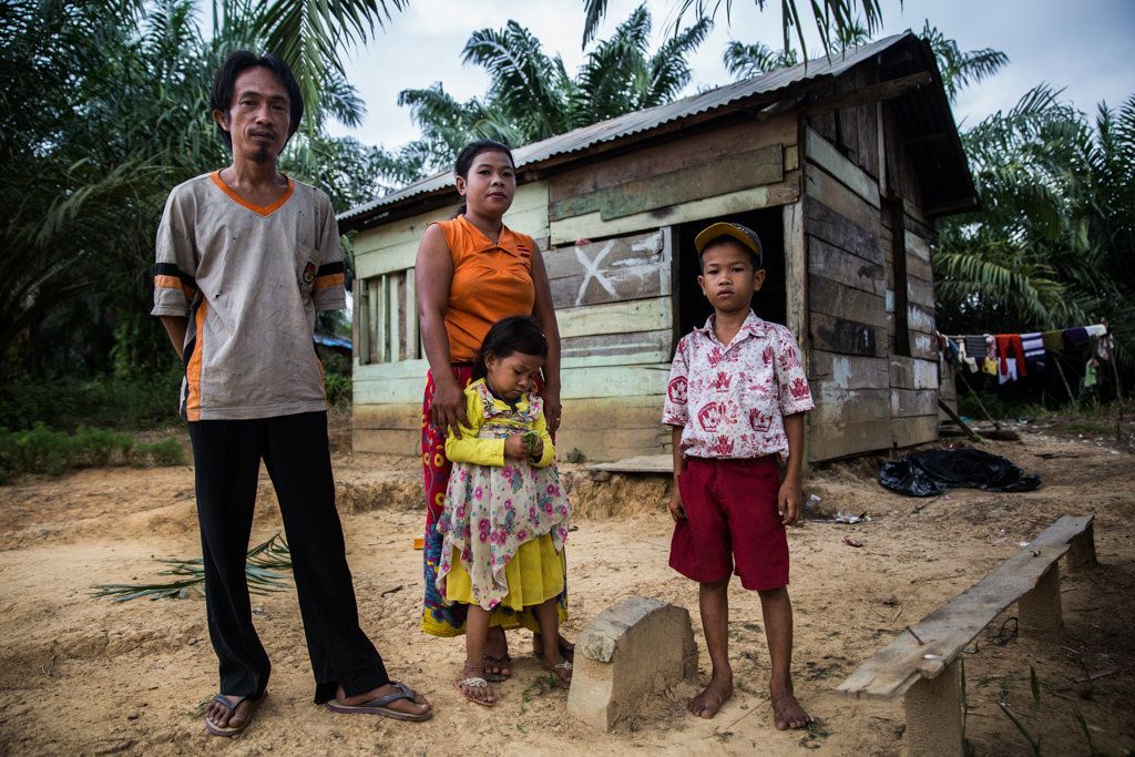 Revan Pragustiawan with his parents and one of his two sisters in front of the house his family built after a palm oil company evicted them from their ancestral home.