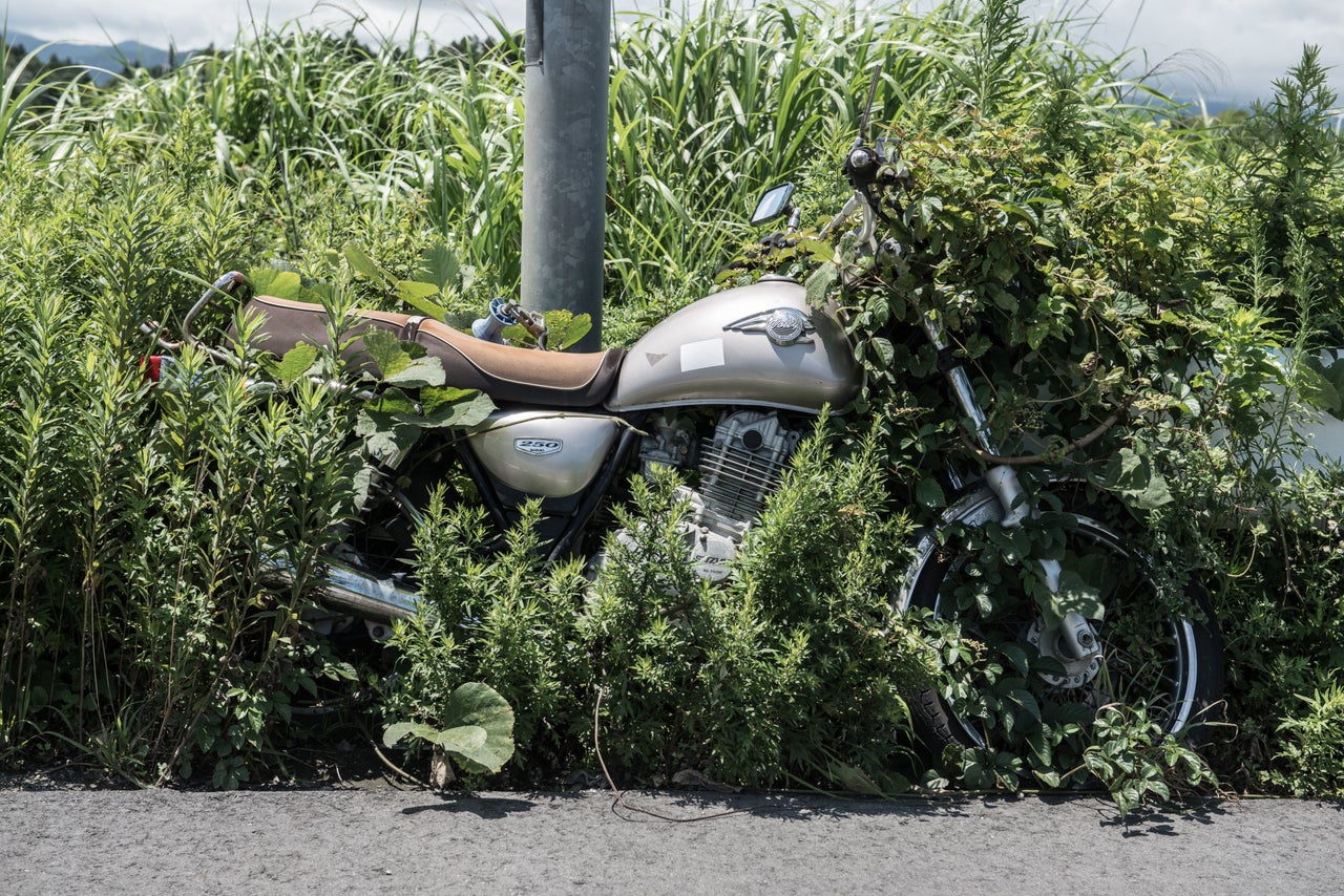 A motorbike left next to a lamppost in 2011. Since the disaster weeds have grown over much of the bike's wheel.