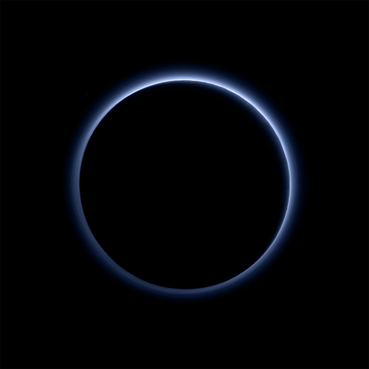 Pluto's haze layer looks blue in this picture taken by the New Horizons spacecraft. The high-altitude haze is thought to be similar to that seen at Saturn's moon Titan. The source of both hazes likely involves sunlight-initiated chemical reactions of nitrogen and methane, leading to soot-like particles (tholins) that grow as they settle toward the surface. This image was generated by software that combines information from blue, red and near-infrared images to replicate the color a human eye would perceive as closely as possible.