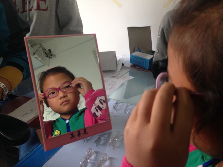 A girl tries on her first pair of glasses at the Qin'an County Hospital.