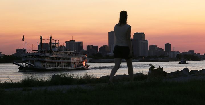 A woman walks atop an earthen levee on the Mississippi River in the Lower 9th Ward as the Steamboat Natchez passes in August 2015 in New Orleans. The city is ringed by hundred of miles of levees to protect against flooding.