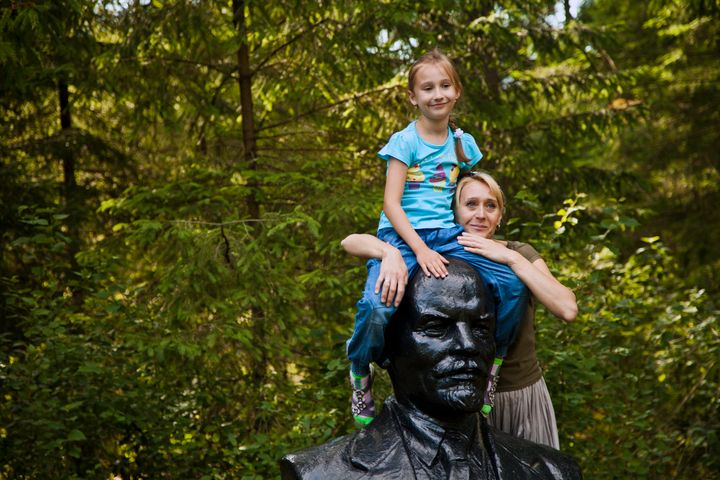 Mother and daughter playfully pose atop Lenin's head.