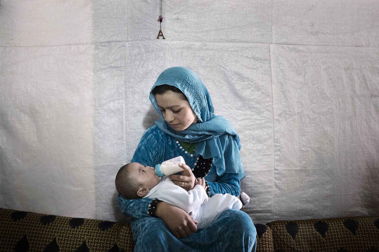 Syrian refugee Samira, 14, feeds her 7-month-old son inside their tent shelter in Rawda, Bekaa Valley.