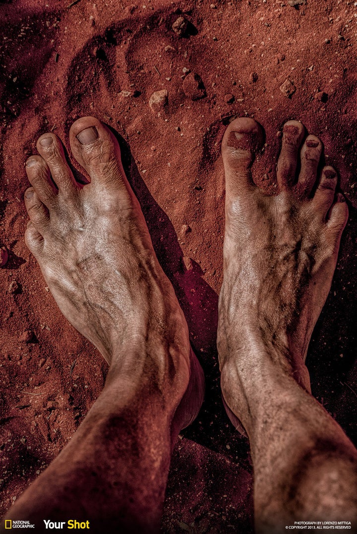 In "The Oz Dream," a photographer's feet are covered in the red clay soil of Australia.