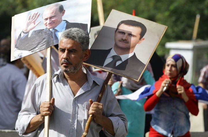 A Syrian man holds up portraits of President Bashar Assad and his Russian counterpart, Vladimir Putin.