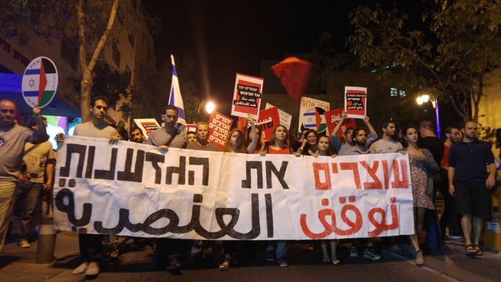 Israeli and Palestinian activists hold a banner that says "Stopping Racism" in Hebrew and Arabic. Some 2,000 people demonstra