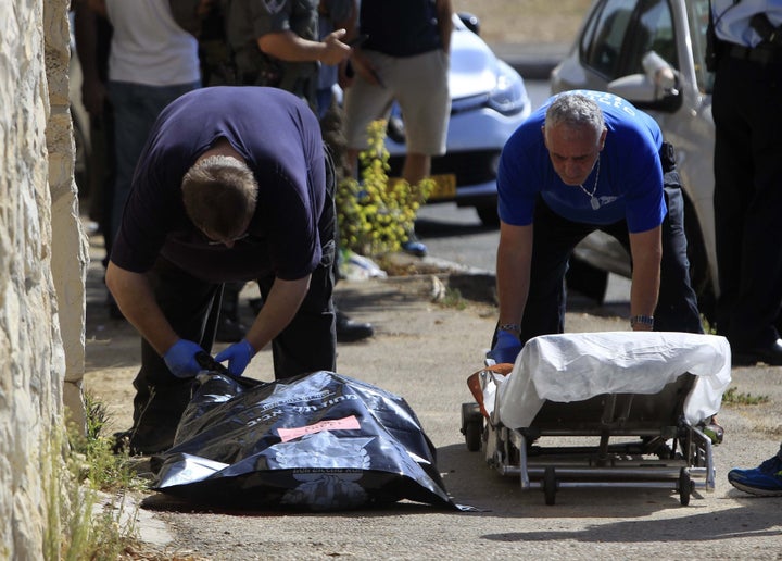 Israeli officials stand near the body of an alleged Palestinian attacker in Jerusalem, Oct. 17, 2015.