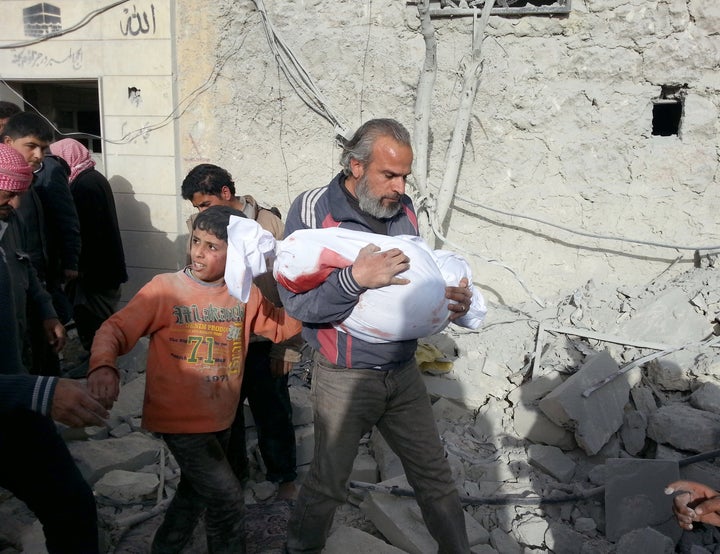 A Syrian man carries the body of a child after a barrel bomb attack by Syrian regime helicopters in Aleppo, Syria, on March 6, 2014.