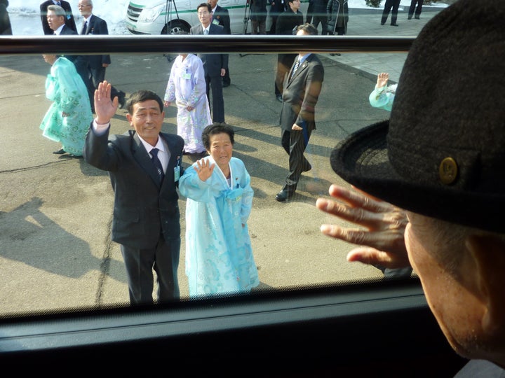 South Korean Kim Se-rin waves goodbye from a bus to his North Korean sister and nephew as he leaves a 2014 family reunion event in the North.