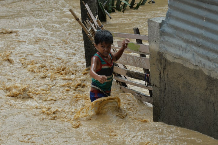 A child wades through floodwaters near his residence at a village in Santa Rosa town, Nueva Ecija province, north of Manila on October 19, 2015, a day after typhoon Koppu hit Aurora province. Residents of flooded farming villages in the Philippines were trapped on their rooftops October 19 and animals floated down fast-rising rivers, as deadly Typhoon Koppu dumped more intense rain. AFP PHOTO / TED ALJIBE (Photo credit should read TED ALJIBE/AFP/Getty Images)