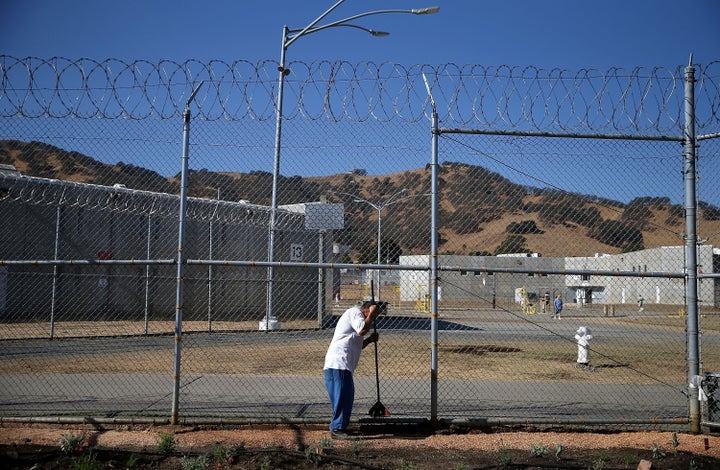 A California State Prison-Solano inmate uses a hand tool to pack decomposed granite while installing a drought-tolerant garden in the prison yard.