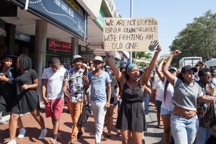 "We are not looking for our own struggle. We're fighting an old one," a student's placard reads.