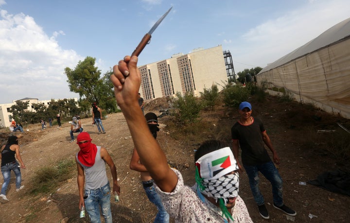 A young Palestinian raises a knife during clashes with Israeli security forces (not pictured) in the West Bank city of Tulkarem on Sunday. Four Palestinians were shot dead and a fifth wounded in attacks on Israelis in east Jerusalem and the West Bank the previous day.