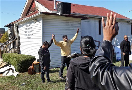 In this Sunday, Oct. 18, 2015 photo, Pastor David Triggs and his wife, Charronda, hold hands and take part in the outdoor service following a fire at the church at the New Life Missionary Baptist Church in St. Louis. Someone has been setting fire to predominantly black churches in the St. Louis area, and investigators are trying to determine if the arsonist is targeting either religion or race. (J.B. Forbes/St. Louis Post-Dispatch