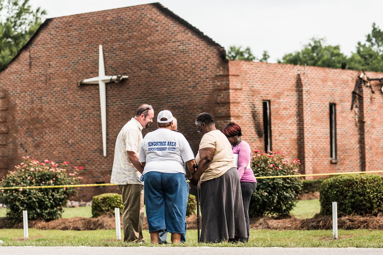 People pray near the burned ruins of the Mt. Zion AME Church July 1, 2015, in Greeleyville, South Carolina.