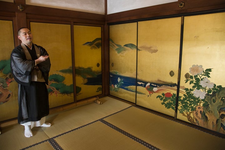 A monk at Shunkoin stands in front of the temple's sliding door panels, which were painted by artist Eigaku Kano.