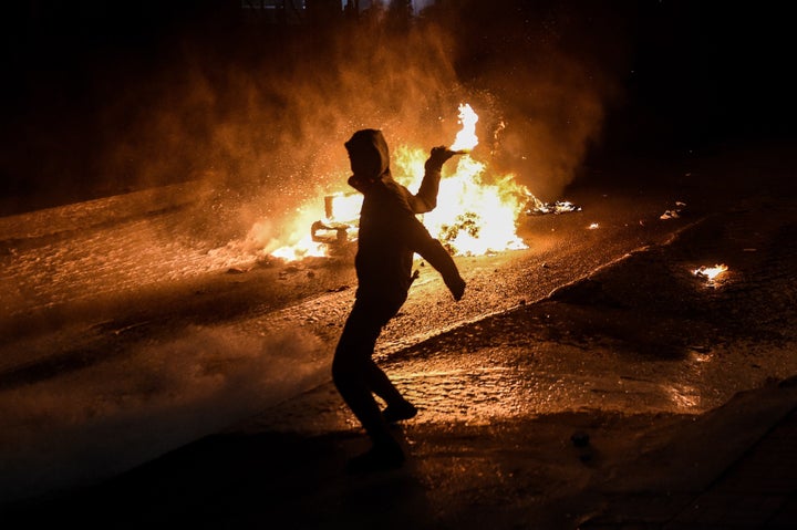 A fire burns in the background as a left-wing militant throws a molotov cocktail toward a water cannon during a demonstration in Istanbul against the deadly attacks in Ankara.