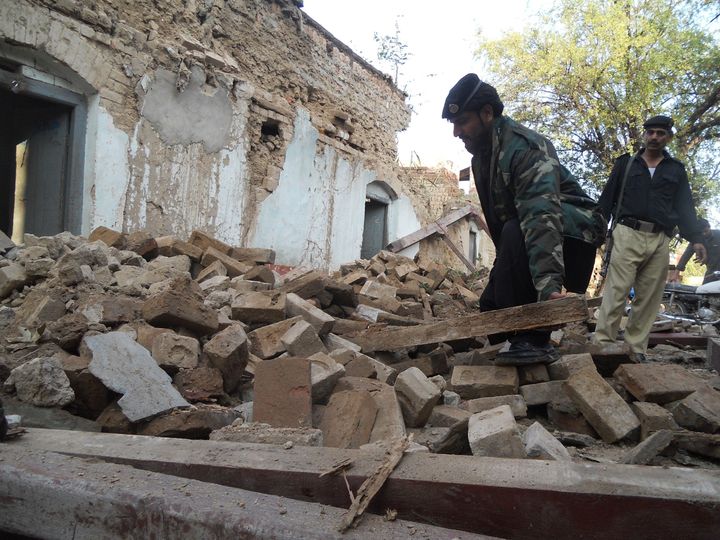 A policeman digs through the debris of collapsed houses in Kohat. 