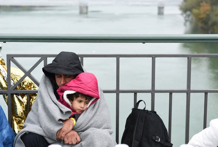 A man and child take shelter from the cold as they wait to cross the Austrian-German border.