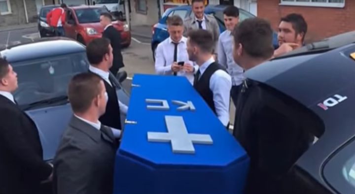 Cable's friends carry the coffin labeled KC, which they created for the faux funeral.