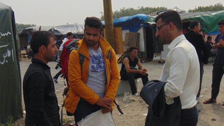 Passarlay and a member of the Afghan Youth Movement UK talk to an Afghan refugee in the "Jungle," a makeshift refugee camp in
